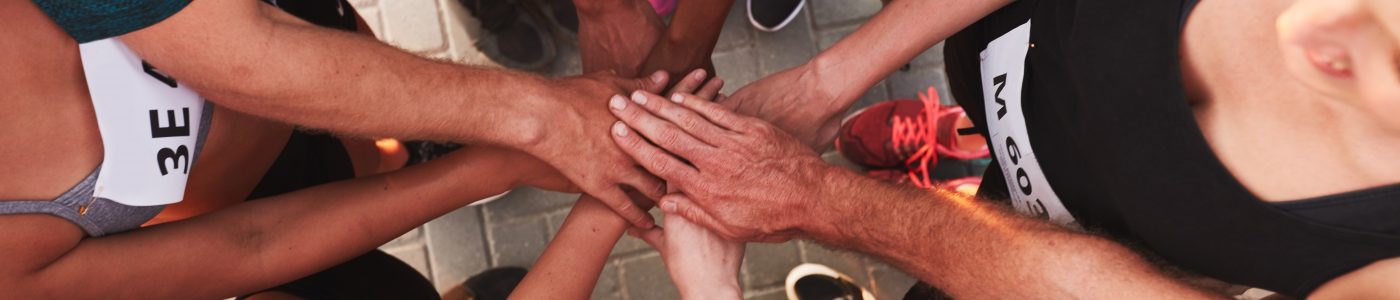 High angle portrait of a sports team standing in a circle with their hands stacked. Team of runners with hands together after competition.